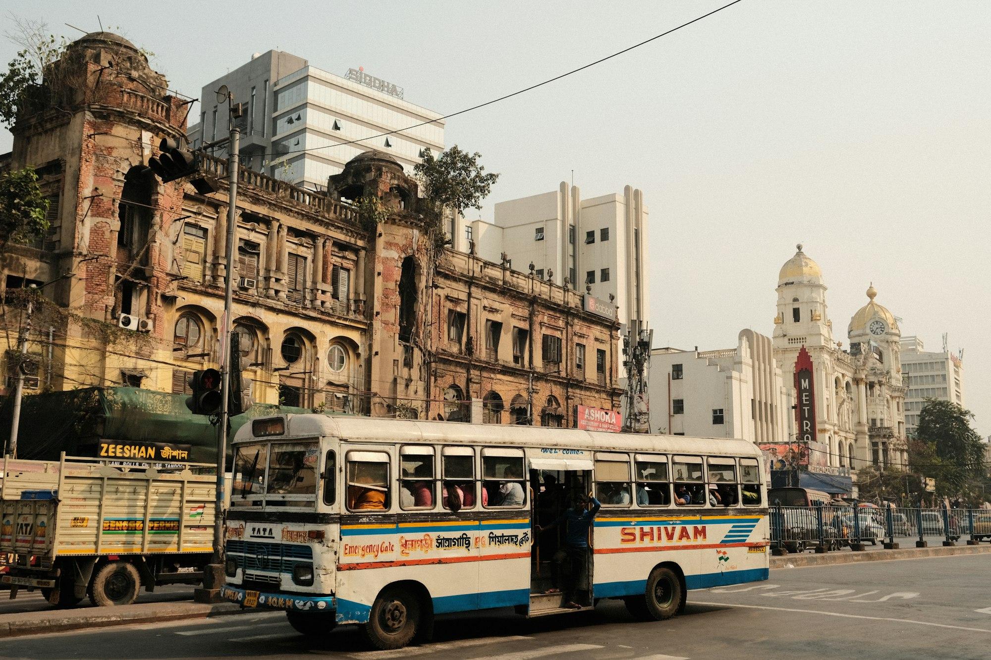 A street in Kolkata with a bus passing tall buildings