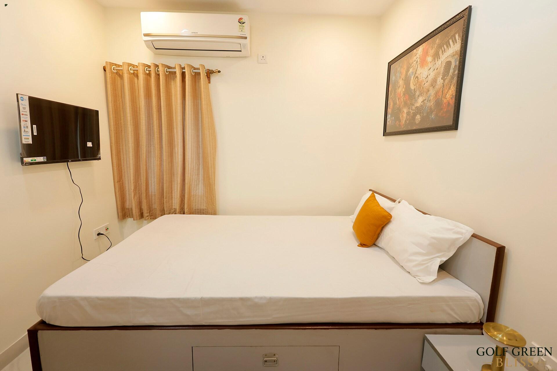 Bedroom two with air conditioning, a wall-mounted television and curtained window