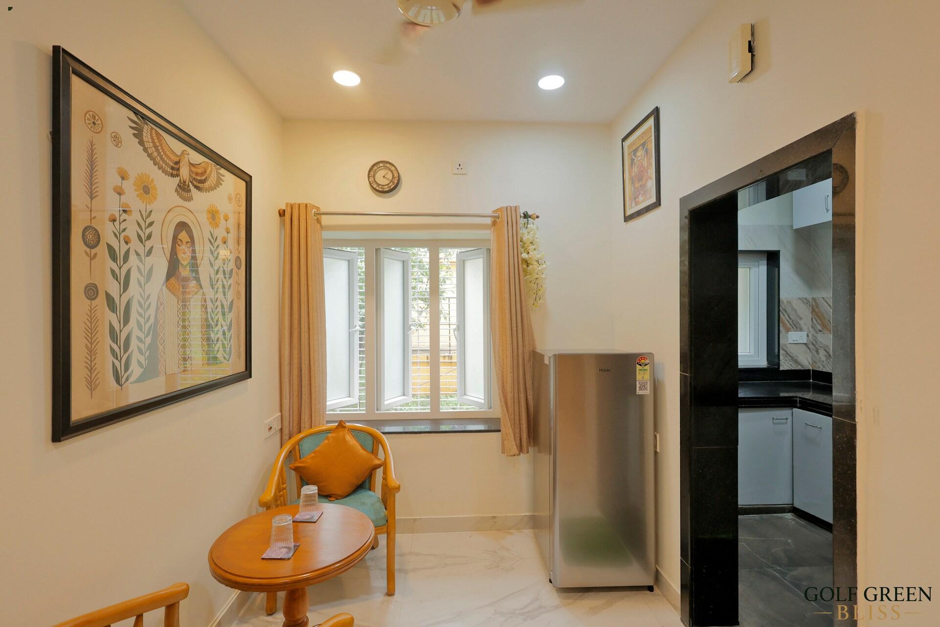 The dining corner with the refrigerator, a framed print and daylight from the window
