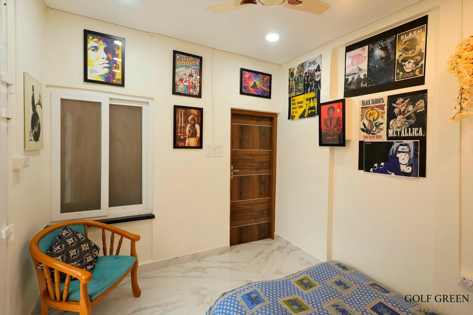 A corner of the apartment with framed prints arranged on the wall beside a window and an armchair