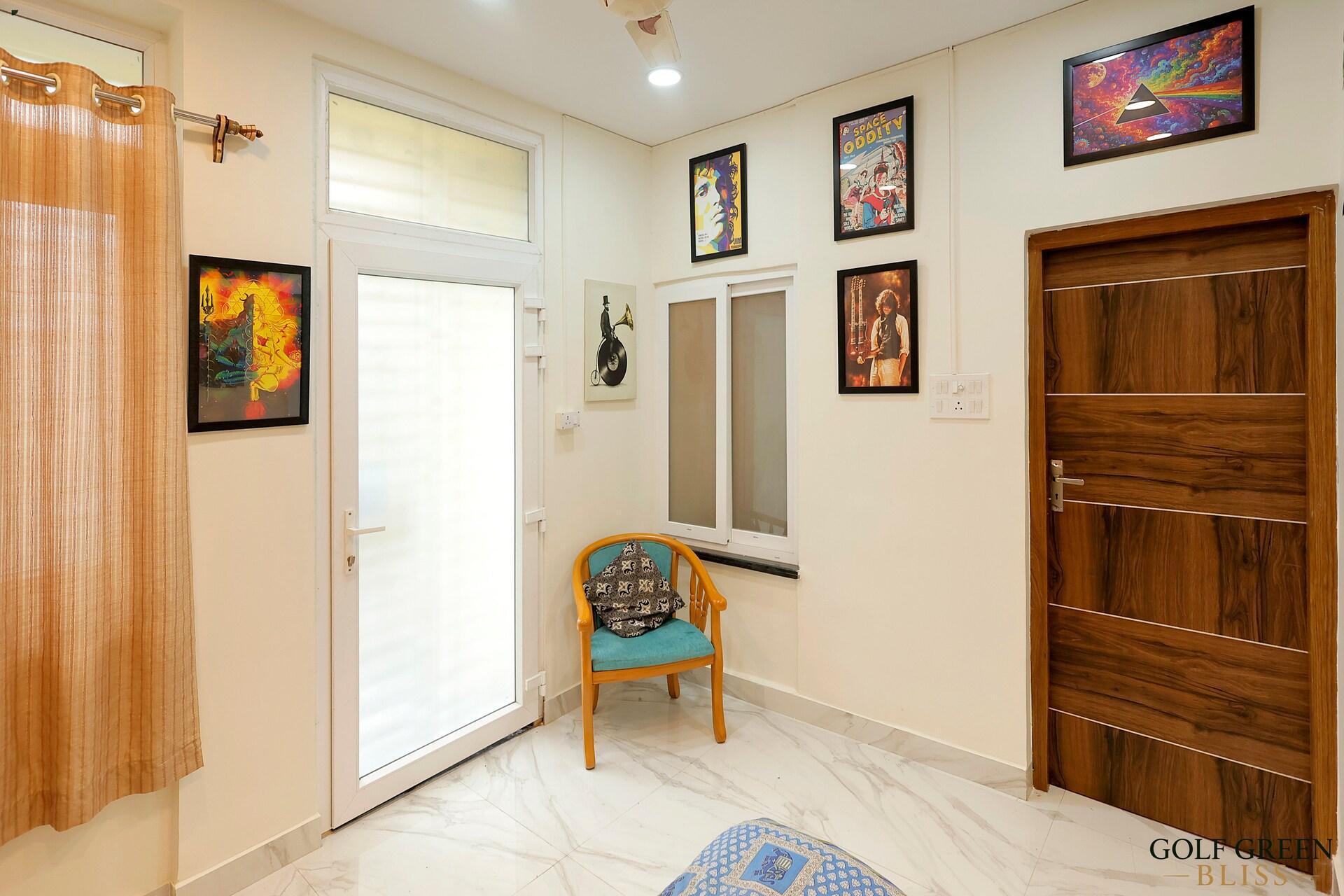 The entrance area with a glazed door, framed prints and an armchair