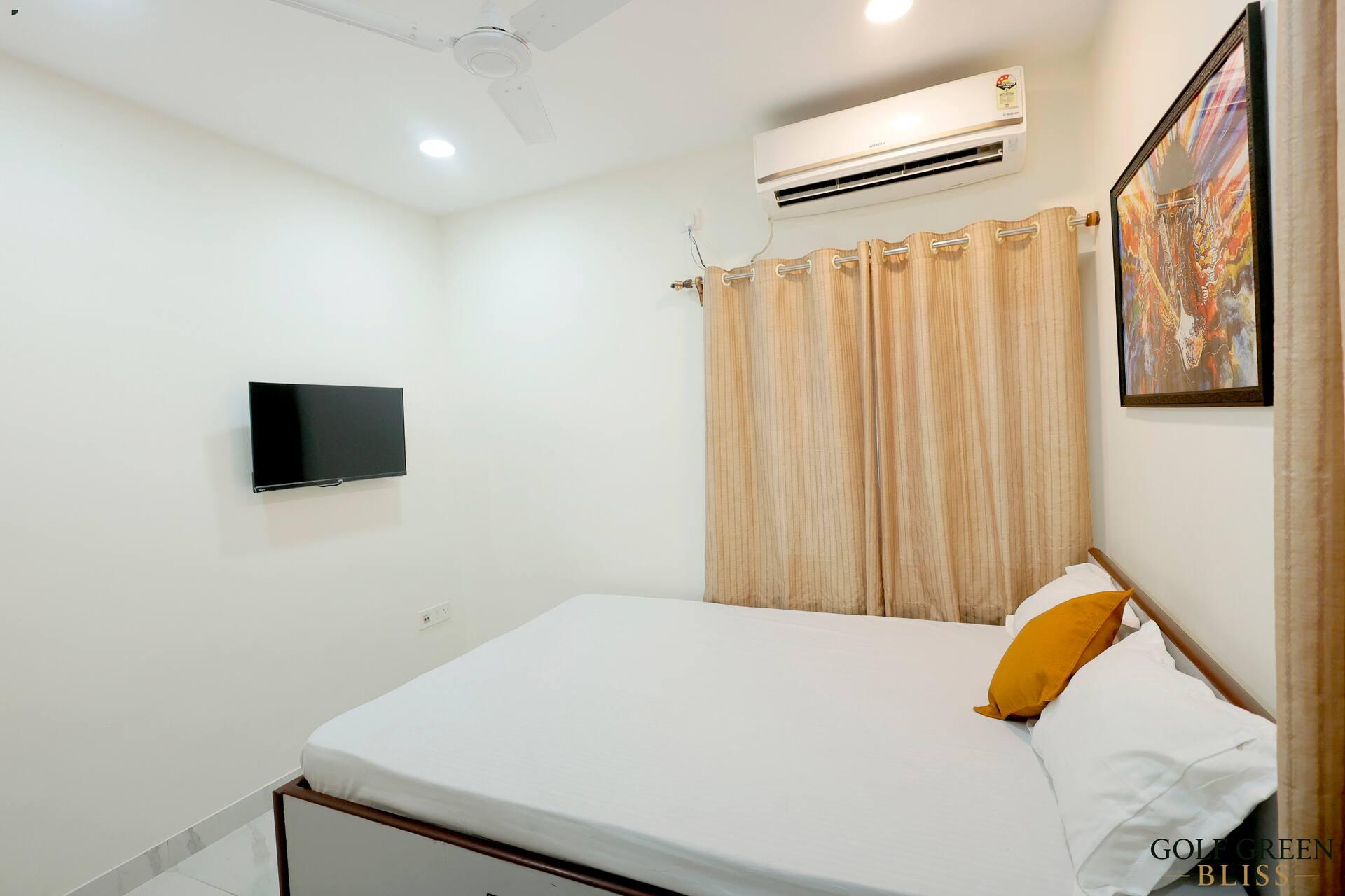 Bedroom two from the far corner, with the television, air conditioning and curtained window