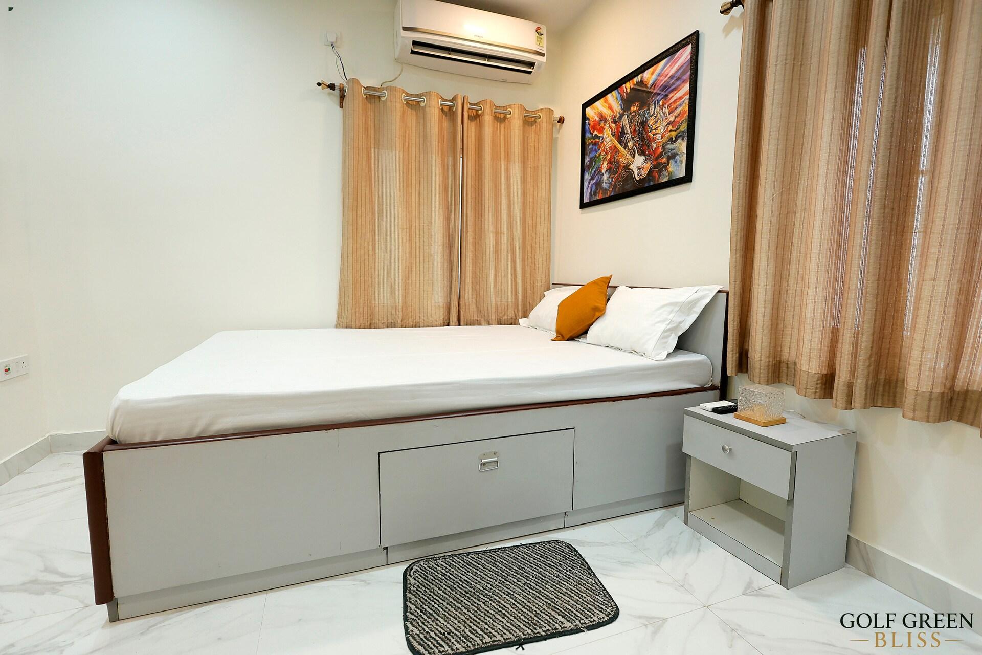 A bed with storage drawers beneath it, below a framed print
