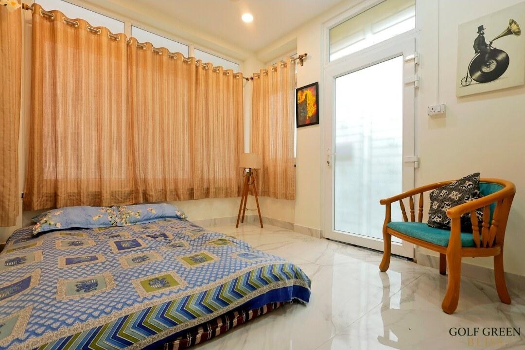 Bedroom three with the floor mattress, tripod lamp and teak armchair beside the glazed door