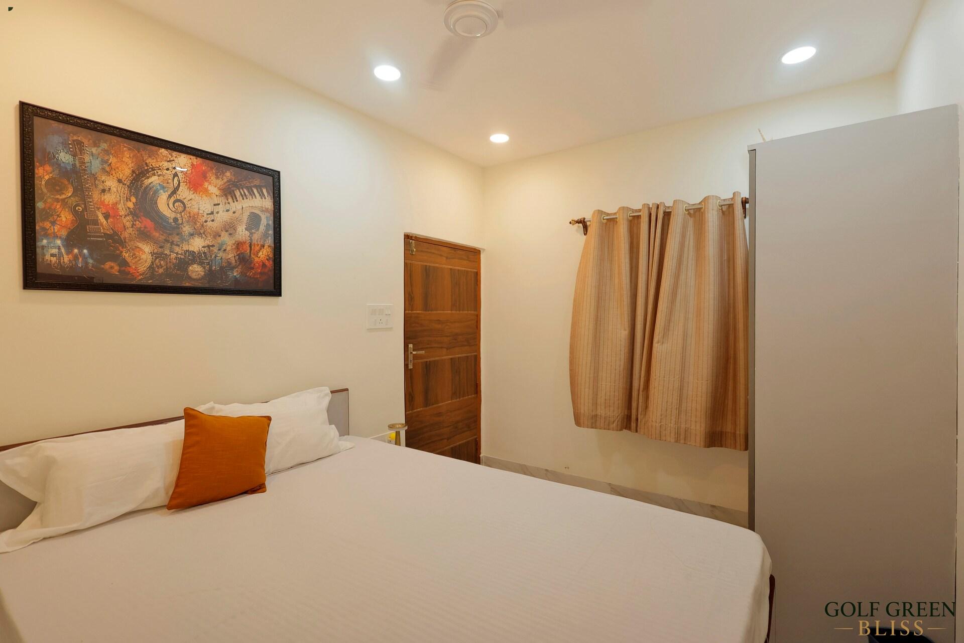 Bedroom two with a queen bed, a framed print above the headboard and a tall wardrobe